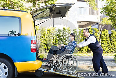 Driver helping man on wheelchair getting into taxi Stock Photo