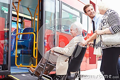 Driver Helping Senior Couple Board Bus Via Wheelchair Ramp Stock Photo