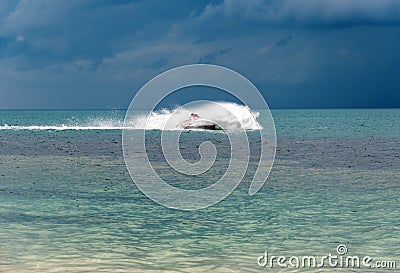 The driver of the jet ski drives a jet ski at high speed, rides at sunset on the sea Stock Photo