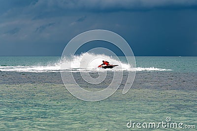 The driver of the jet ski drives a jet ski at high speed, rides at sunset on the sea Stock Photo