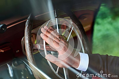 Driver keeps hand on steering wheel of his vintage car Stock Photo