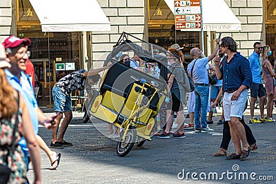 Driver repairs a rickshaw in a crowded square near the Basilica of Santa Maria del Fiore, Florence Editorial Stock Photo