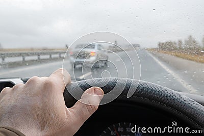 Driver`s hand on the steering wheel of a car that is driving on the highway Stock Photo