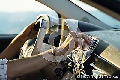 Hand of man with bracelets wipes panel vent with white napkin holding steering wheel driving car Stock Photo