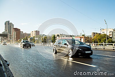 Driving in big city. Drive tuning car in rain on asphalt wet road. Clouds and sun Stock Photo