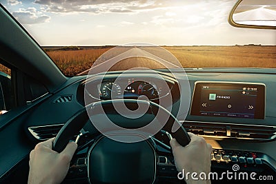 Driving car through a perfect road through fields illuminated by sunrays Stock Photo