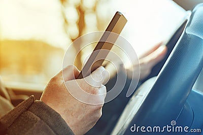 Driving car and using mobile phone to send text message Stock Photo