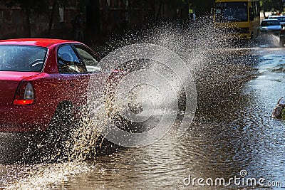Driving cars on a flooded road during floods caused by rain storms. Cars float on water, flooding streets. Splash on the machine. Stock Photo