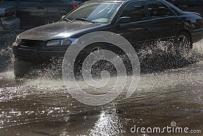 Driving cars on a flooded road during floods caused by rain storms. Cars float on water, flooding streets. Splash on the machine. Editorial Stock Photo