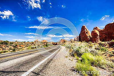 Driving through the-Desert with Monument Rock along the Road During Sunny Day, Arches NP Stock Photo