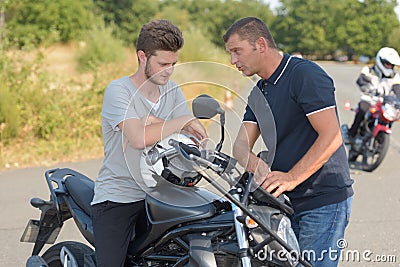 Driving instructor advising young man driving motorbike Stock Photo