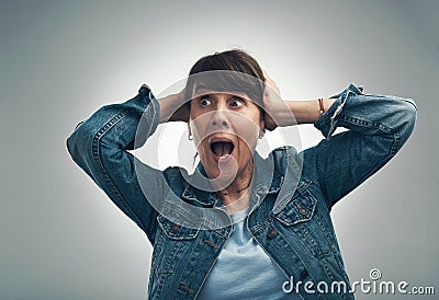 This is driving me bonkers. Studio shot of a senior woman looking shocked against a grey background. Stock Photo