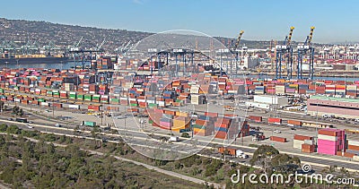 DRONE: Cars and trucks drive along freeway running past the colorful port of LA Editorial Stock Photo