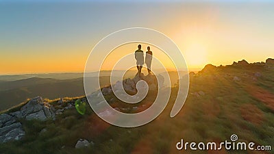 DRONE: Cinematic shot of active young couple observing the evening landscape. Stock Photo