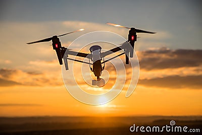 Drone with digital camera flying in sky over field on sunset Stock Photo