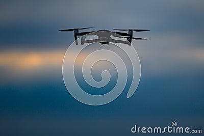 Drone flying on dark evening or night sky Stock Photo