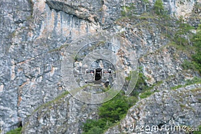 Drone flying with mounted digital camera used for photographing and filming. quadcopter flying hovering over mountains Stock Photo