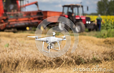 Drone in front of tractor and combine harvester in field Stock Photo