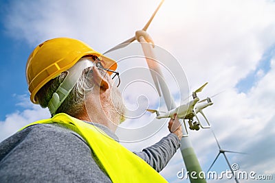 Drone operated by construction worker inspecting wind turbine Stock Photo