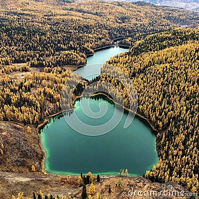 A drone photo of an autumn forest with yellow and green trees on a cliff and two large turquoise lakes Stock Photo