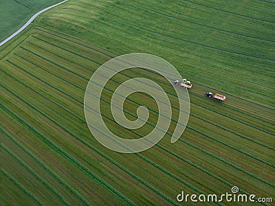 Drone shot of agricultural field with tractors harvesting hay Stock Photo