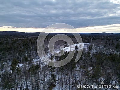 Drone shot over a snowy forest under cloudy sky of the nightfall time Stock Photo