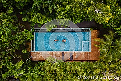 drone view of a swimming pool in the jungle , couple men and women in a pool in the rainforest Stock Photo