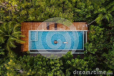 drone view of a swimming pool in the jungle , couple men and women in a pool in the rainforest Stock Photo