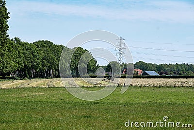 Dronten, the Netherlands June1,2021:Grassland with tractor mower and rake, grass ready to be ensiled.Dutch farmers race Editorial Stock Photo