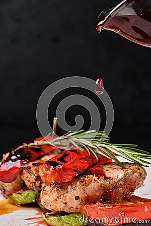 A drop of cherry sauce is pouring onto a grilled veal Stock Photo