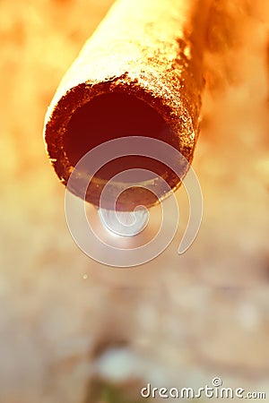 A drop of water hangs from an old water pipe, against the background of a gray concrete wall. Ecological concept of the ancient Stock Photo