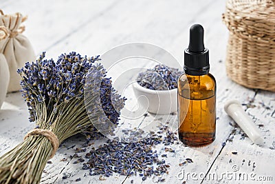 Dropper bottle of lavender essential oil, sachet bags and bouquet of dried lavender flowers on white table Stock Photo