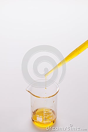 Dropping oil from a pipette into a test beaker Stock Photo