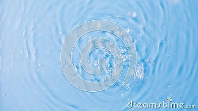 Drops fall down into clear fresh water on light blue background view from above Stock Photo