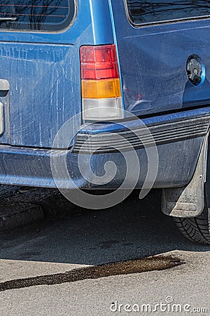 Drops of gasoline flow on asphalt from a parked car. Environmental pollution by combustible motor fuel. Risk of fire. Editorial Stock Photo