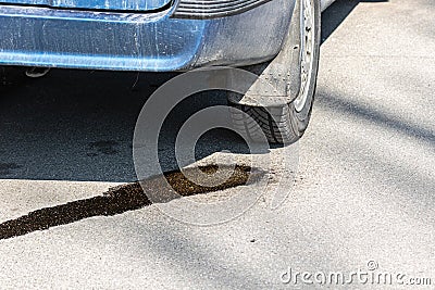 Drops of gasoline flow on asphalt from a parked car. Environmental pollution by combustible motor fuel. Risk of fire. Stock Photo