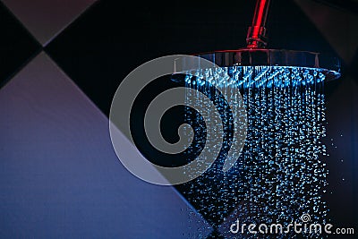 Drops of water fall from a watering can in the shower in blue light. Water drops close-up. Flow of water. Stock Photo