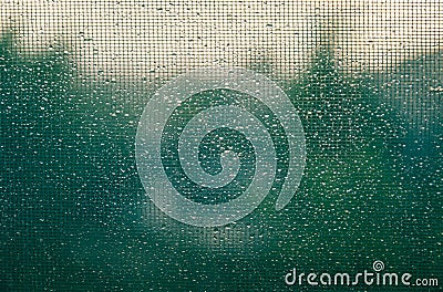 Drops of water on glass and grid close-up. Raindrops of white water falling down on glassa nd grid Stock Photo