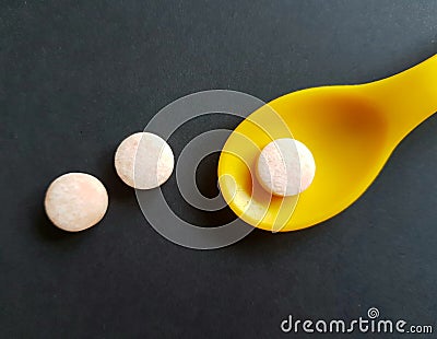 Drops on yellow spoon over black. Medicine concept. Stock Photo