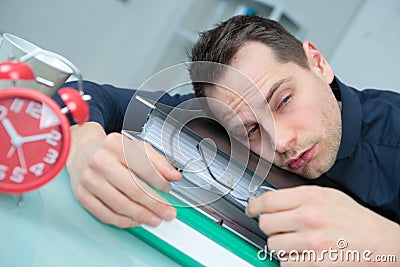 Drowsy man slumped on folders Stock Photo