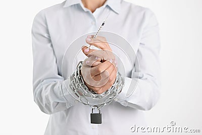 Drug addict is holding syringe with his hands tied by chain Stock Photo