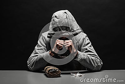 The drug addict was arrested for drug use at the table. suffering from addiction on a dark black background. Stock Photo