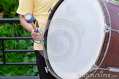 Drum sticks hitting the drum. The drummer is drumming bass drum in a marching band in the parade. Stock Photo