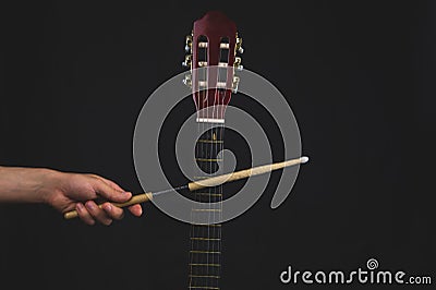 Drumstick in the hand and guitar fretboard close up. acoustic musical instrument Stock Photo