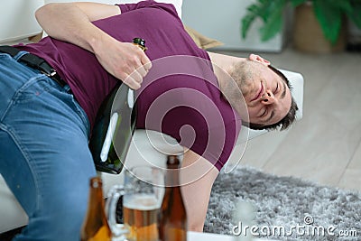 Drunk businessman sleeping with bottle vodka on sofa Stock Photo