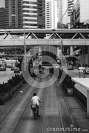 Drunk Chinese man on a bicycle riding in the area dedicated to double-decker trams in Hong Kong Editorial Stock Photo