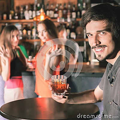 Drunk man sitting at bar, drinking cocktail, looking at girls Stock Photo