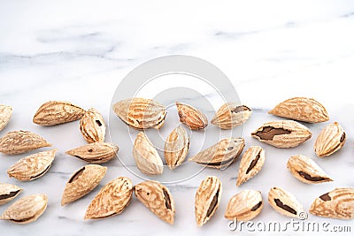 Dry almonds in golden shells are scattered on a white table. Healthy food high in protein, omega-3s, antioxidants and vitamins. Stock Photo