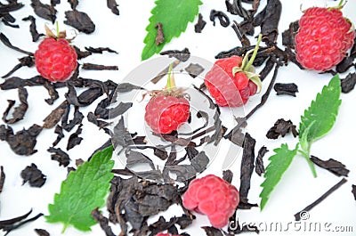 dry black tea in a wooden spoon on a white plate with raspberries and mint. healthy healing berry tea Stock Photo