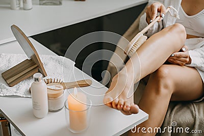 Dry brushing body brush for exfoliating dry skin, lymphatic drainage and cellulite treatment. Woman brushing skin leg Stock Photo